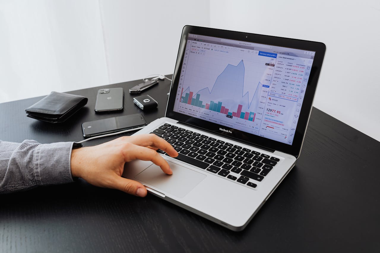 Person analyzing stock market data on a laptop at a desk.